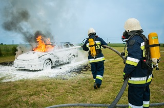 image of car fire being extinguished by fire fighters